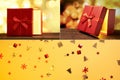 A collage of a red gift box and confetti. A golden light comes out of the box. Christmas background with copy space Royalty Free Stock Photo