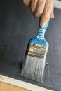 An artist`s hand holding a blue brush and canvas