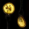 Collage of three slices of lemons on the fork on dark black background. silhouette of a fork in the back light. Drops of juice