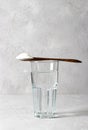 Collagen powder in spoon on glass of water on gray background. Healthy and antiage concept. Vertical format Royalty Free Stock Photo