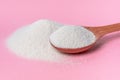 collagen powder and spoon over pink background, concept of cosmetic skin care