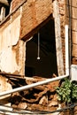 Collapsed and abandoned building with a plug hanging from a window without glass