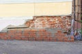 The collapsed corner of the old brick house is repaired with a fresh masonry of red brick.