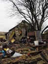 A collapsing moss covered abandoned rural wooden building surrounded with broken discarded objects and rocks in a countryside back