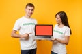 Colleagues couple in white t-shirt inscription volunteer hold laptop pc computer, blank empty screen isolated on yellow Royalty Free Stock Photo