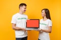 Colleagues couple in white t-shirt inscription volunteer hold laptop pc computer, blank empty screen isolated on yellow Royalty Free Stock Photo