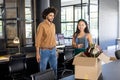 Colleagues discussing office relocation while unpacking box in modern workspace Royalty Free Stock Photo