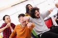 Colleagues having fun on work at the office. Girls pushing boys on chairs with wheels. Multiethnic group of successful start up