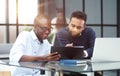 colleagues sitting together at a table in a modern office talking and using a laptop Royalty Free Stock Photo