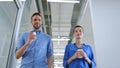 Colleagues walking with paper cups in office. Business woman and man talking Royalty Free Stock Photo