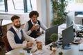 Colleagues watching content on computer monitor at workplace, laughing. multiethnic, sharing, funny content, casual business