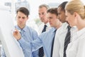 Colleagues watching young businessman write on whiteboard Royalty Free Stock Photo