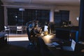 Colleagues working late in office, analyzing data on computer screen together Royalty Free Stock Photo