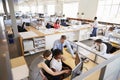 Colleagues working at a womans workstation in a busy office Royalty Free Stock Photo