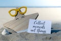 COLLECT MOMENTS NOT THINGS text on paper greeting card on background of funny starfish in glasses summer vacation decor