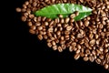 Collected coffee beans in the corner with leaf on black