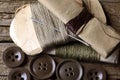 A COLLECTION OF ASSORTED MILITARY REPAIR KIT THREAD AND DARNING YARN, BROWN BUTTONS AND NEEDLES ON A WOODEN BOARD Royalty Free Stock Photo