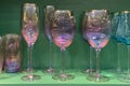 Collection of beautiful colourful glasses on wooden cabinet shelf