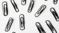 A collection of black paper clips arranged on a white surface Royalty Free Stock Photo