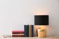 Collection of books, glasses and lamp on table near white wall. Space for text Royalty Free Stock Photo