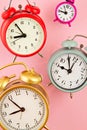 Collection of bright colorful alarm clocks over the pink background