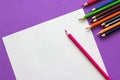 Collection of colored pencils on a purple background and white sheet of paper top view and copy space. Back to school Royalty Free Stock Photo