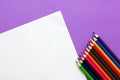 Collection of colored pencils on a purple background and white sheet of paper top view and copy space. Back to school Royalty Free Stock Photo