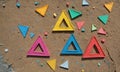 collection colorful triangular shapes, including pink, blue, yellow, and red, scattered on sandy surface with Royalty Free Stock Photo