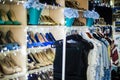 Collection of colourful shoes on shelves in interior. Dresses hang on a hanger in a row