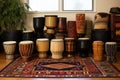 collection of djembe drums in various sizes on a rug