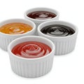 Four ramekins filled with different sauces, including ketchup, barbecue sauce, and mustard, isolated on white background Royalty Free Stock Photo