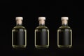 Collection glass bottles for cosmetic, perfume, drink with black label, cork, yellow liquid in a row on dark black background.