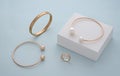 Collection of golden bracelets and ring on white box on blue background Royalty Free Stock Photo