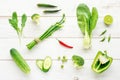 Collection of green organic vegetables with red chili accent on wooden table.