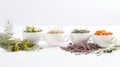 a collection of herbs and spices in white cups on a white background