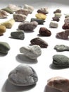 A collection of lying in rows of multicolored small natural stones of minerals, lying on a white background