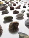 A collection of lying in rows of multicolored small natural stones of minerals, lying on a white background