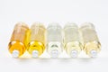 Collection lying transparent bottles with different pale colors liquid, cosmetic product, perfume or drink and silver cap on white Royalty Free Stock Photo