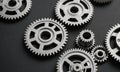 collection metallic gears in various sizes and orientations, arranged in scattered pattern against dark