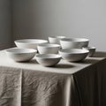A collection of minimalist, white ceramic bowls is arranged on a table covered with a Royalty Free Stock Photo