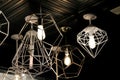 a collection of modern, geometric pendant lights hanging from a dark ceiling in cage like frames in silver and gold Royalty Free Stock Photo