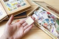 Collection of postage stamps of different countries in the old box lying on a wooden table. Hand holds a blank postage stamp