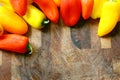 A collection of Red and Yellow Sweet Peppers Bordering Wood Cutting Board Royalty Free Stock Photo