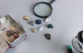 collection of semiprecious stones on gray table with magnifying glass