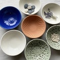 A collection of seven ceramic bowls arranged on a textured fabric surface Royalty Free Stock Photo