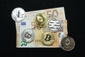 Collection of silver and gold cryptocurrency coins on a 50 euro banknote