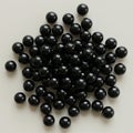 A collection of small black marbles is arranged on a light, flat surface. These spherical Royalty Free Stock Photo