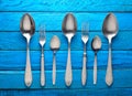 Collection of spoons and forks on a blue wooden background.