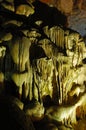 Spotlit stalactites in a cave forming grotesque shapes.