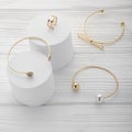 Collection of three bracelets and ring on white platforms on wooden background with copy space Royalty Free Stock Photo